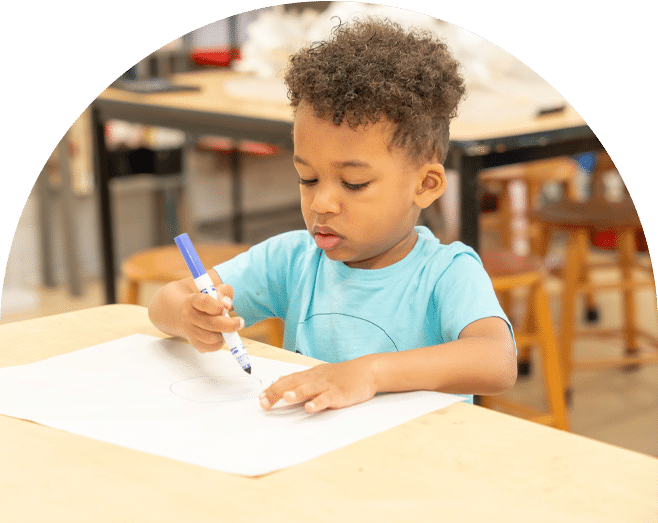 Young boy at school drawing with a marker